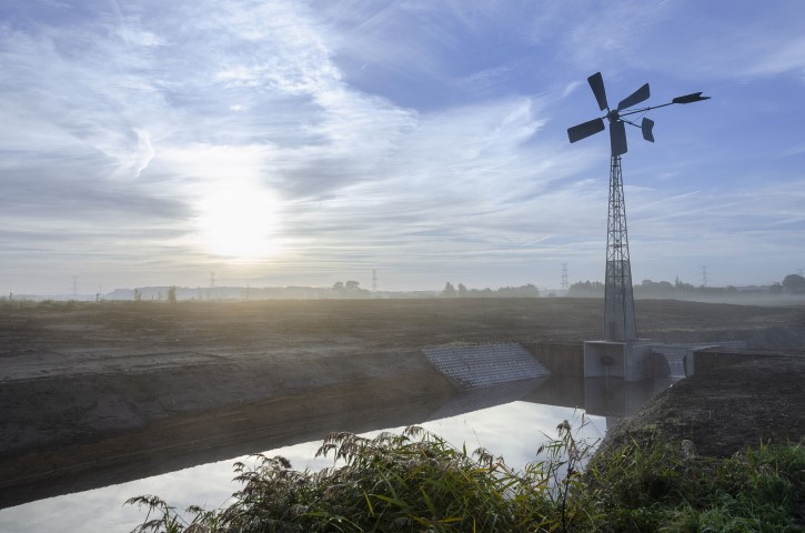 landschap met stuw, watermolen, waterloop en ondergaande zon 