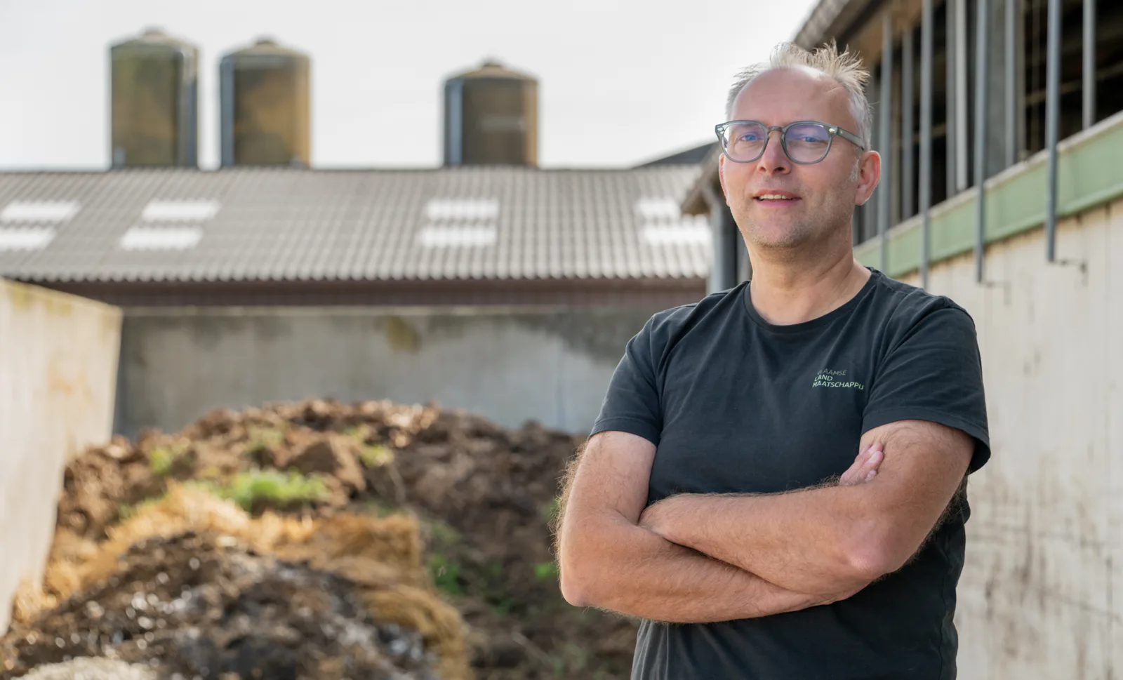 Maarten bij een vaste mestopslag op een landbouwbedrijf. Drie mestdichte wanden en mestsappen die correct worden opgevangen, zij